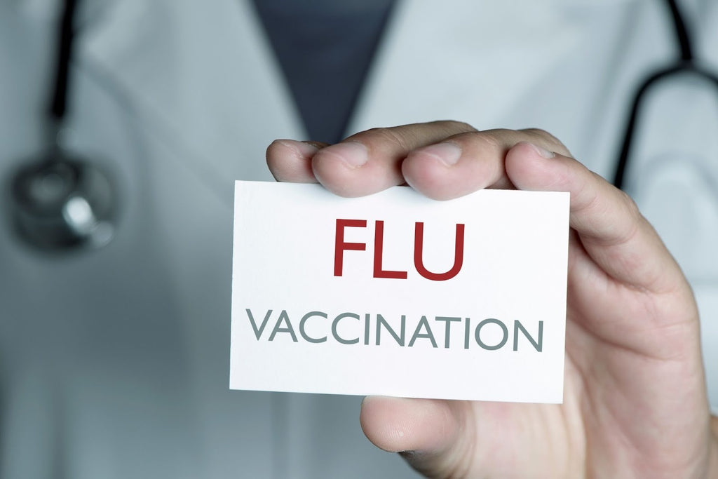 A hand holding up a card that says “flu vaccination.”